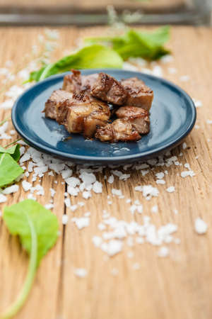 Medium Rare Fried Diced Marinated Beef on Blue Ceramic Plate on Wood Panel with Sea Salt and Vegetable Decorated.の写真素材