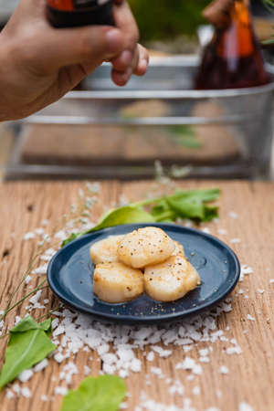 Fried Scallops Topping with Pepper on Blue Ceramic Plate on Wood Panel with Sea Salt and Vegetable Decorated.の写真素材
