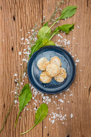 Fried Scallops Topping with Pepper on Blue Ceramic Plate on Wood Panel with Sea Salt and Vegetable Decorated.の写真素材