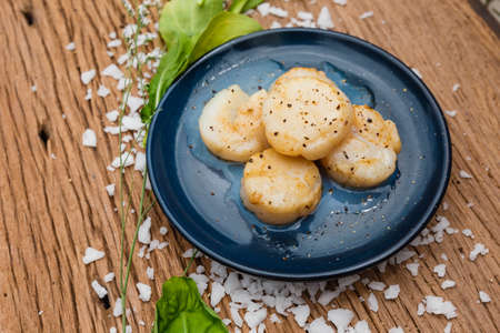 Fried Scallops Topping with Pepper on Blue Ceramic Plate on Wood Panel with Sea Salt and Vegetable Decorated.の写真素材