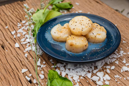 Fried Scallops Topping with Pepper on Blue Ceramic Plate on Wood Panel with Sea Salt and Vegetable Decorated.の写真素材