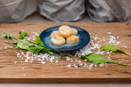 Fried Scallops Topping with Pepper on Blue Ceramic Plate on Wood Panel with Sea Salt and Vegetable Decorated.の写真素材