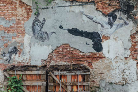 Painted Chinese Man Jumping Kick Cat in The Air on Old Red Brick Wall from The Street of George Town. Penang, Malaysia.のeditorial素材