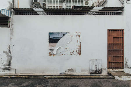 White Clean Wall with Rusted Red Wall with Ripped Poster Trace from The Street of George Town. Penang, Malaysia.のeditorial素材