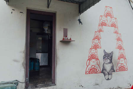 Painted Grey Color Cat Looking Red Cartoon Cats on The Wall from The Street of George Town. Penang, Malaysia.のeditorial素材