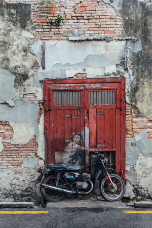 Painted Man Riding a Real Motorcycle on The Red Door with Red Brick Wall from The Street of George Town. Penang, Malaysia.のeditorial素材