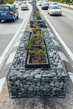 Traffic island with stones in wire metal box on the road in Kuala Lumpur, Malaysia.