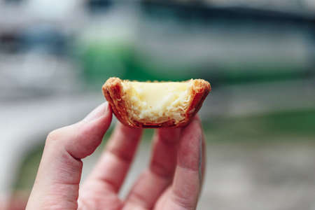 Bited egg tarts in hand in Kuala Lumnpur, Malaysia.