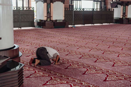 A man is praying in Putra Mosque in Wilayah Persekutuan Putrajaya, Malaysia
