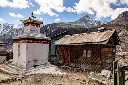 Tibetan stupa with rural wooden house with Black mountain with snow on the top is background at Thangu and Chopta valley in winter in Lachen. North Sikkim, India.のeditorial素材