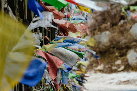 Tear colorful Tibetan prayer flags waving and swaddled with bridge over frozen river at Thangu and Chopta valley in winter in Lachen. North Sikkim, India.の写真素材