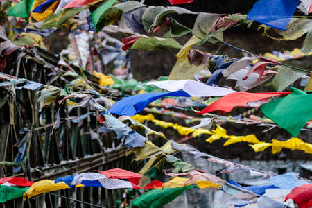 Tear colorful Tibetan prayer flags waving and swaddled with bridge over frozen river at Thangu and Chopta valley in winter in Lachen. North Sikkim, India.の写真素材