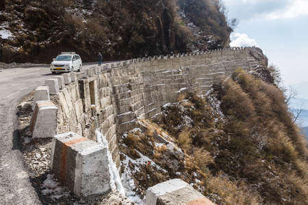 Stone mountain with tourist car and road. Background is mountain and blue sky in winter near the way to Tsomgo Lake in Gangtok. Sikkim, India.のeditorial素材