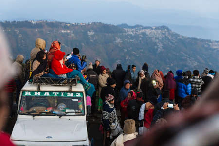 People are sitting on the car with crowd for seeing the first light of new year's day at dawn with mountain villages and Kangchenjunga mountain in winter at Tiger Hill, Darjeeling. India.のeditorial素材