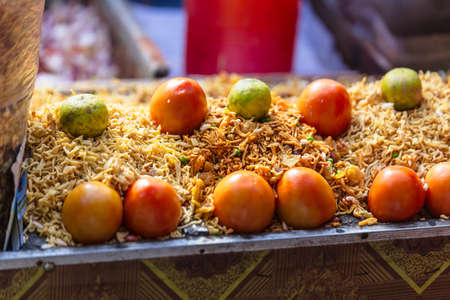 Sev with tomato and lime is a popular Indian snack food consisting of small pieces of crunchy noodles made from chickpea flour paste at street local market in Darjeeling. India.の写真素材