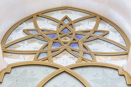 Glass window decorated with golden geometric form in Sheikh Zayed Grand Mosque with blue sky in the morning at Abu Dhabi, UAE.のeditorial素材