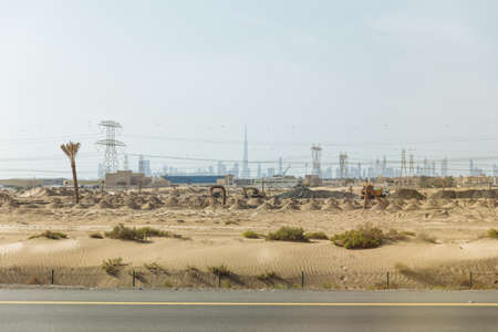 Desert beside of the main road with electricity posts and silhouette buildings in background at Dubai.の写真素材