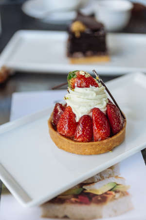 Strawberry tart topping with cream, eatable gold paper and chocolate sticks at the cafe in Dubai.の写真素材