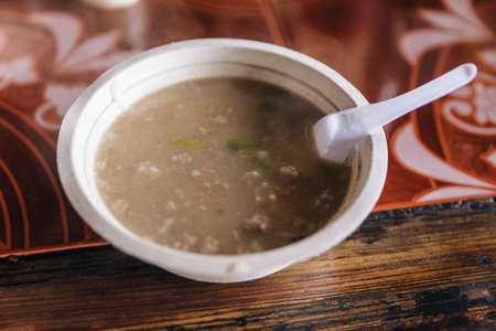 Pork boiled rice with stream in foam bowl with plastic spoon at food market near Kew Mae Pan in Chiang Mai, Thailand.の写真素材