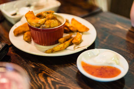 Fried potato with peel served in the red cup with mayonnaise and spicy sauce at the restaurant in Chiang Mai, Thailand.の写真素材