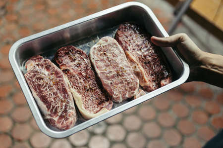 Marinated raw wagyu beef with marble texture that defrost on stainless steel plate in Bangkok, Thailand.の写真素材