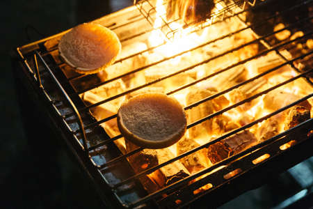Burger buns grill with burning charcoal with fire on the stove with grill on top in Bangkok, Thailand.の写真素材