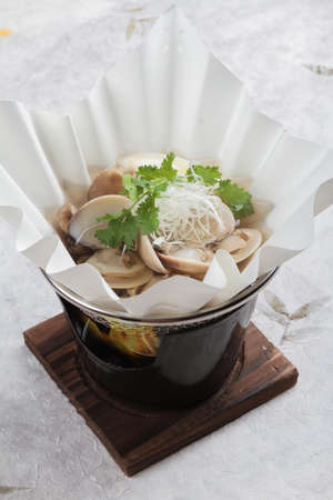 Japanese Clam Soup with Clear Broth (Asari no ushiojiru) with sliced Japanese scallion and coriander served in hot paper bowl on washi (Japanese paper).の写真素材