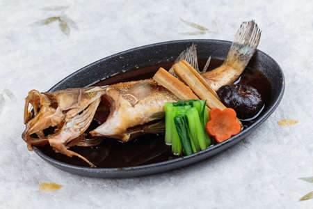 Fried snapper with radish, carrot, shiitake and choy sum in hot plate on washi (Japanese paper).の写真素材