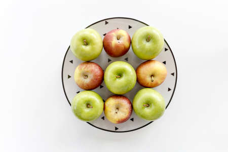 Top view of Pattern Red and green apples in white plate with black triangles pattern on white background.の写真素材