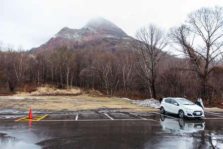 Mountain with snow and fog on the top and trees below at carpark of Noboribetsu Bear Park in Hokkaido, Japan.のeditorial素材