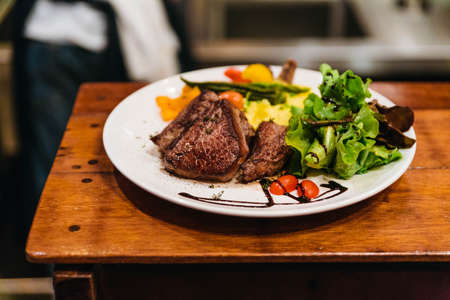 Stir fried beef steak served with vegetable side dish and salad topping with balsamic dressing.の写真素材
