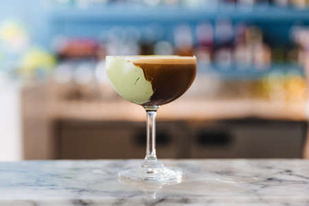 Coffee cocktail with green paste in wine glass on marble top counter.の写真素材