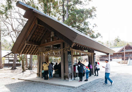 Holy water shrine with tourists at The Hokkaido Shrine (Hokkaido Jingu) in winter in Sapporo....