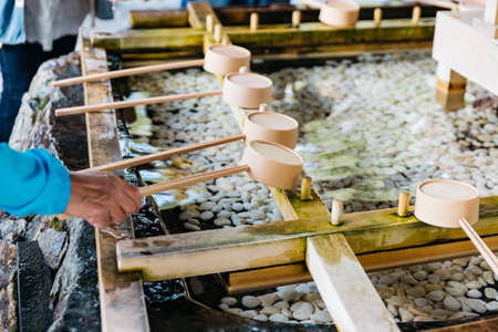 Holy water shrine with tourists scooping water for washing their hands before going to shrine at The Hokkaido Shrine (Hokkaido Jingu) in winter in Sapporo. Hokkaido, Japan.の写真素材