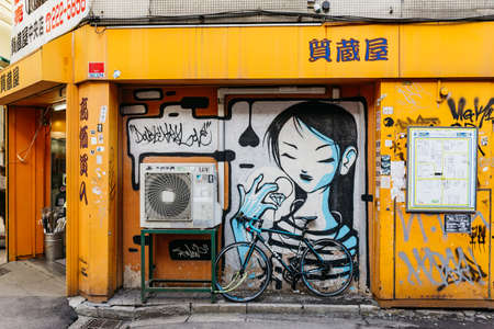 Graffitti on the wall of yellow building with pull over bicycle at Sapporo in Hokkaido, Japan.のeditorial素材