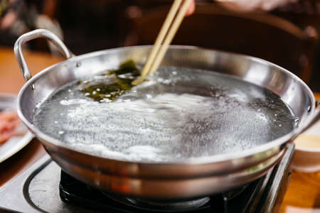 Boiling soup in hot pot stirred by chopsticks at the restaurant in Sapporo. Hokkaido, Japan.の写真素材