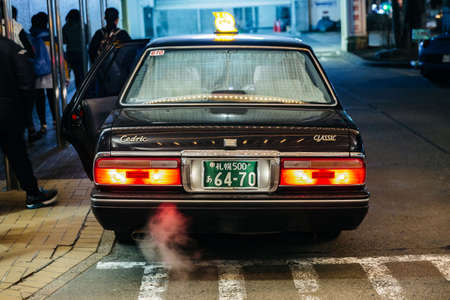 Pull over black color taxi with red light and smoke from intake on the road at night in Sapporo....