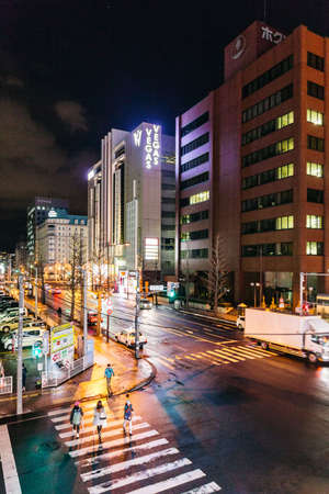 Sapporo night cityscape with buildings turn on the lights, moving cars and people walking in...