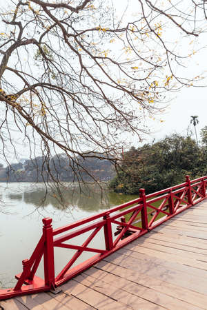 Red Bridge at Hoan Kiem Lake with tress and reflected shadow and branches in foreground in Hanoi, Vietnam.の写真素材