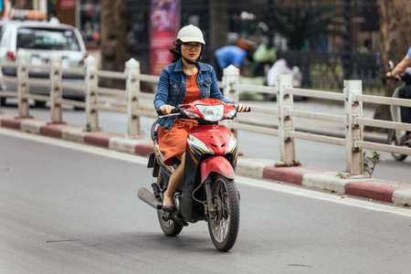 Woman riding motorcycle on the road in Hanoi, Vietnam.のeditorial素材