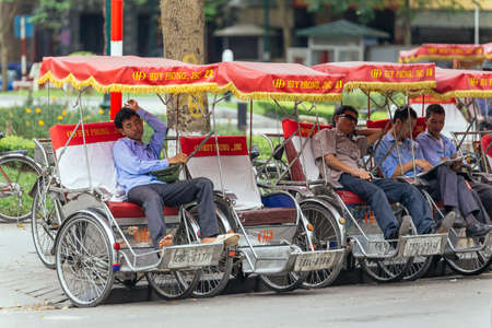 Tricycles with drivers waiting for service on the street in Hanoi, Vietnam.のeditorial素材