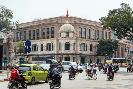 Hanoi Stock Exchange, Colonial architecture with moving cars and motorcycles on the road in Hanoi, Vietnam.のeditorial素材