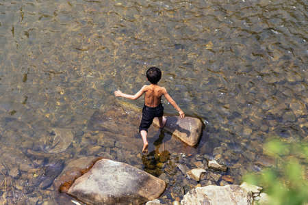 Boy walking on the rock over the river at Cat Cat Village in Sa Pa, Vietnam.