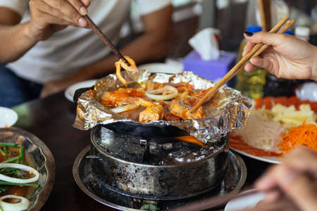 Grilling salmon and onion on foil over hot pan at the restaurant in Sa Pa, Vietnam.の写真素材
