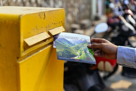 Man right hand sending postcard in yellow post box in summer in Sa Pa, Vietnam.の写真素材