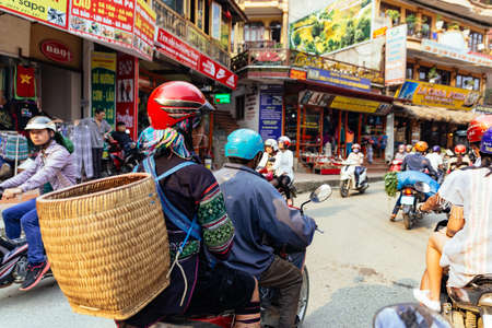 Hill tribe woman carry basket on her back and sit in back seat of motorcycle at the market area in summer in Sa Pa, Vietnam.のeditorial素材