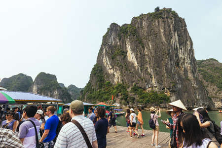 Boat stop with many tourists waiting for traveling inside limestone cave with limestone island in background in summer at Quang Ninh, Vietnam.のeditorial素材