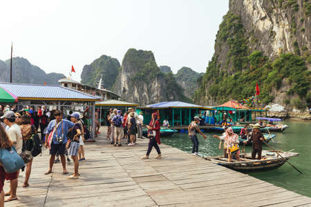 Boat stop with many tourists waiting for traveling inside limestone cave with limestone island in background in summer at Quang Ninh, Vietnam.のeditorial素材