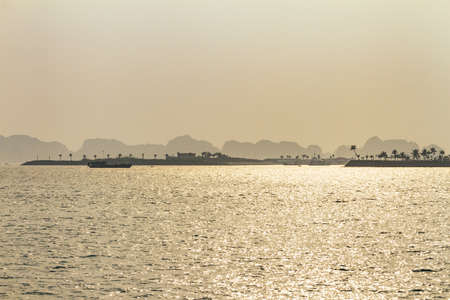 Tourists boats are cruising on the emerald waters with thousands of towering limestone islands in...