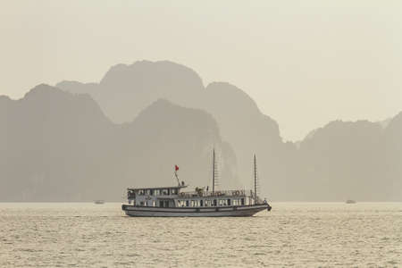 Tourists boats are cruising on the emerald waters with thousands of towering limestone islands in...